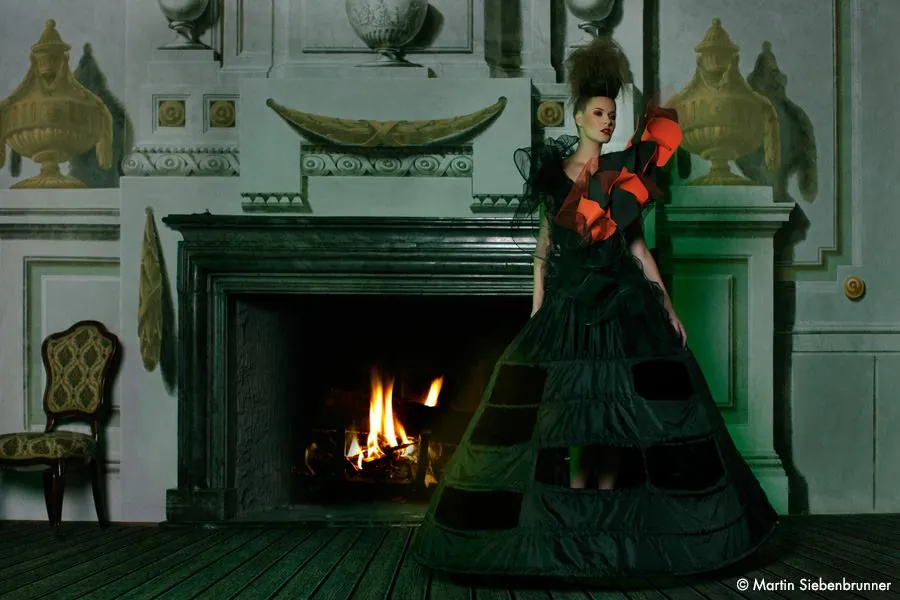 Model im Abendkleid vor einem Kamin in einem historischen Salon