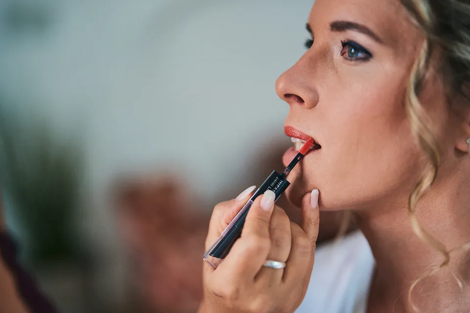 Nahaufnahme: Lippenstift wird im Profil aufgetragen, Augen-Make-up gut sichtbar